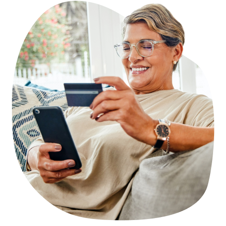 Woman smiling holding credit card in one hand and phone in the other hand