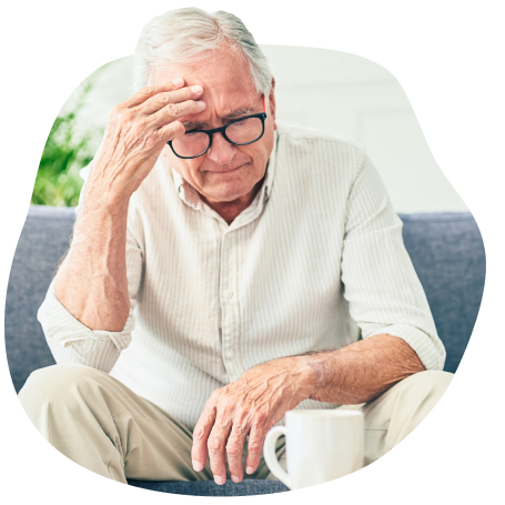 A man with glasses sits with a distressed expression, holding his head in his hand.